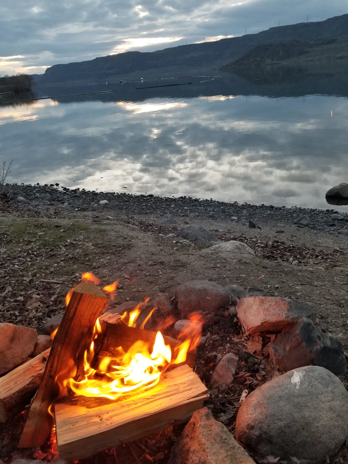 Campfire on the lakeshore at dusk